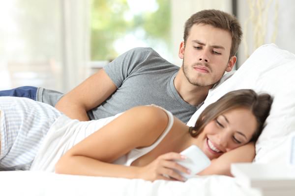 He has no reason to be suspicious, yet his jealousy is ignited when he sees her on her phone. (Antonio Guillem/Shutterstock)